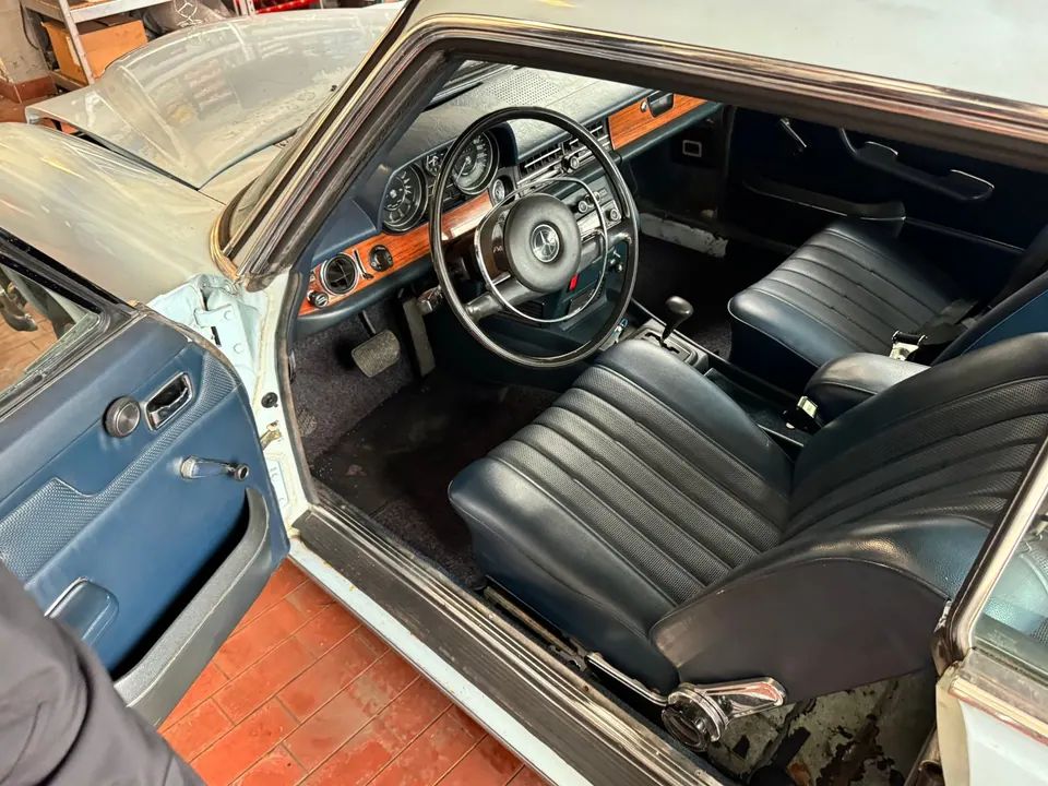Vintage Car Interior: Steering wheel, black leather seats, and orange-brown wood trim